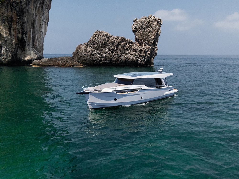 Greenline 42 motor yacht cruising on clear blue water with rocky coastal cliffs in the background.