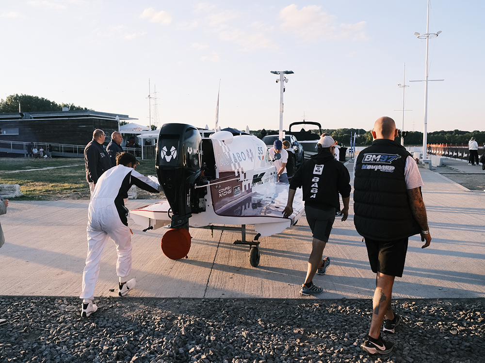 Crew members wheel the Molabo-powered electric Formula-4 race boat along the dock at the Mons Water Grand Prix event.