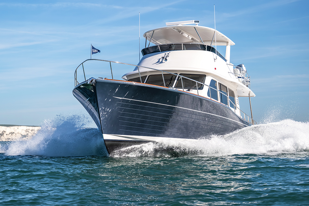 Grand Banks 54 pushing through the sea towards you with blue skies behind
