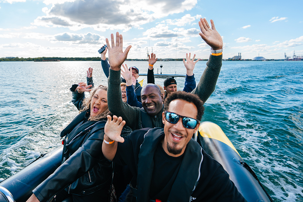 people on an open RIB ride lifting their arms and smiling