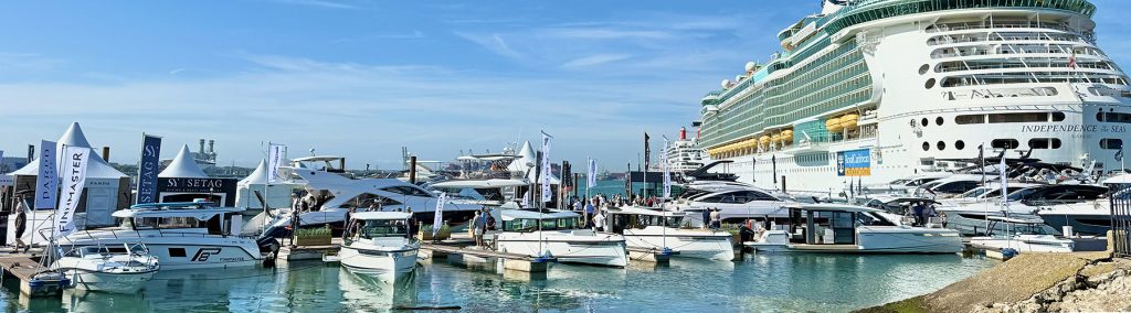 powerboats lined up on a pontoon with a cruise sip behind at Southampton Boat Show