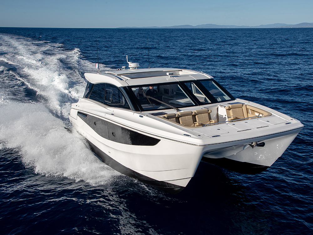 Aquila 46 Coupe power catamaran cruising at speed in clear blue water.