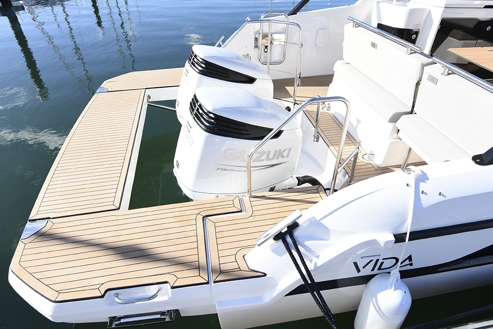 Twin Suzuki outboards on teak bathing platform with ladder and transom seating aboard a Bavaria VIDA 33 motor yacht.