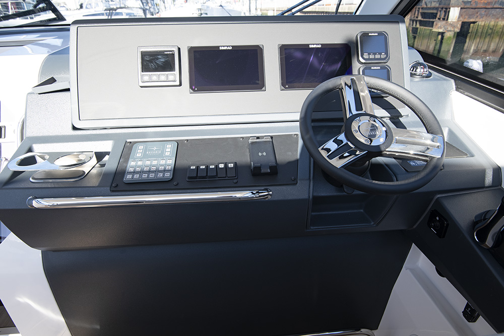 Helm station with steering wheel, dual Simrad displays, and electronic controls aboard a Bavaria VIDA 33.