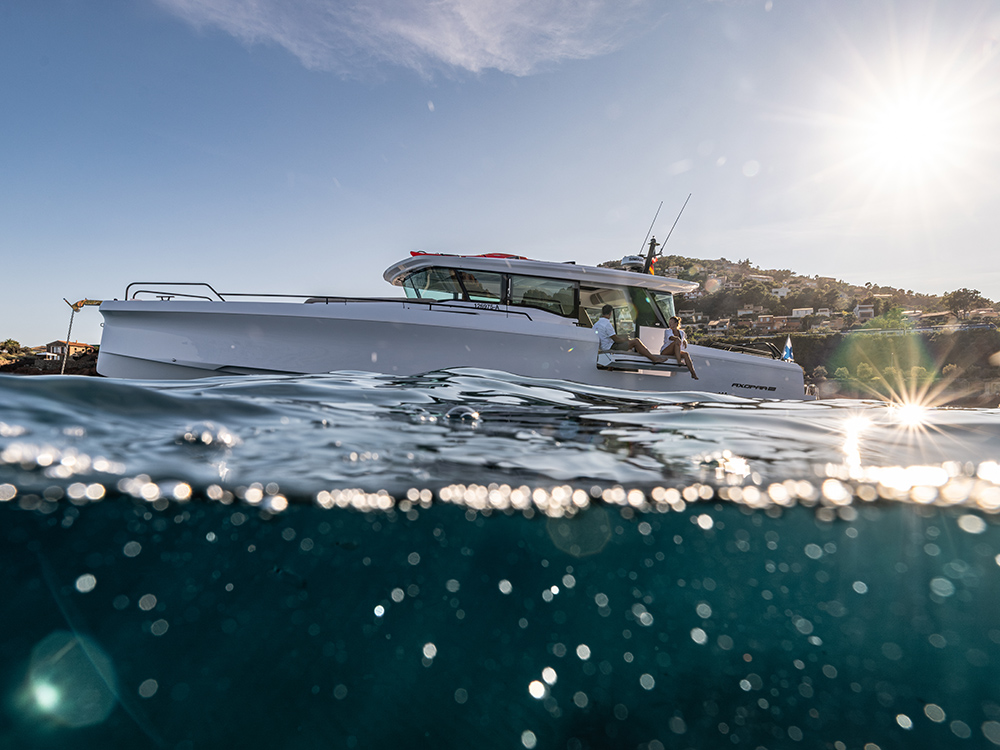Axopar 45 cruising off a sunny coastline with passengers relaxing on deck.