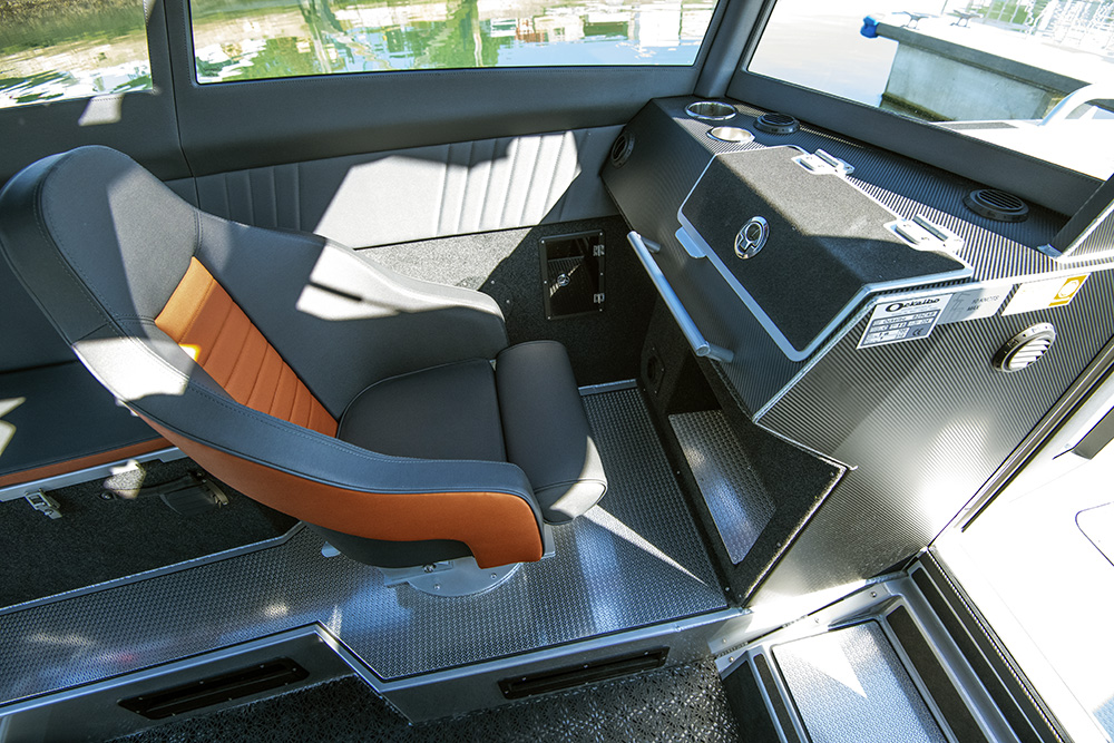 Ockelbo B25 CAB helm seat and console featuring orange trim upholstery and storage compartments.