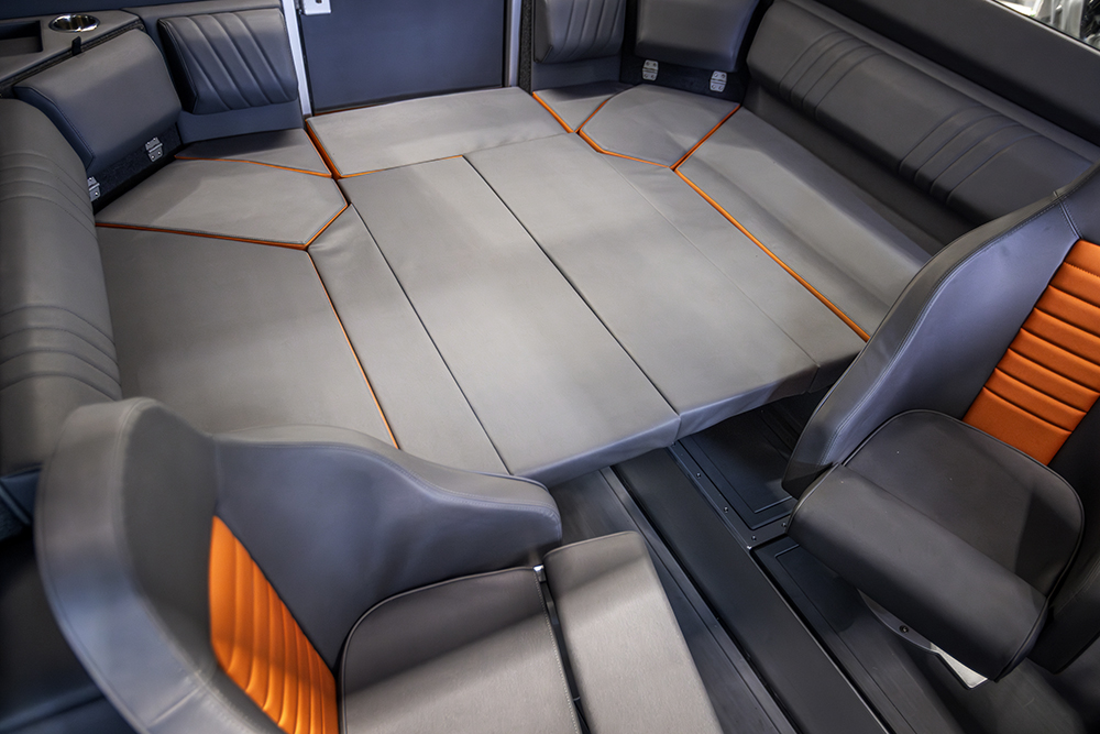 Convertible cabin seating layout forming a full-width berth with grey upholstery and orange accent panels on Ockelbo B25 CAB