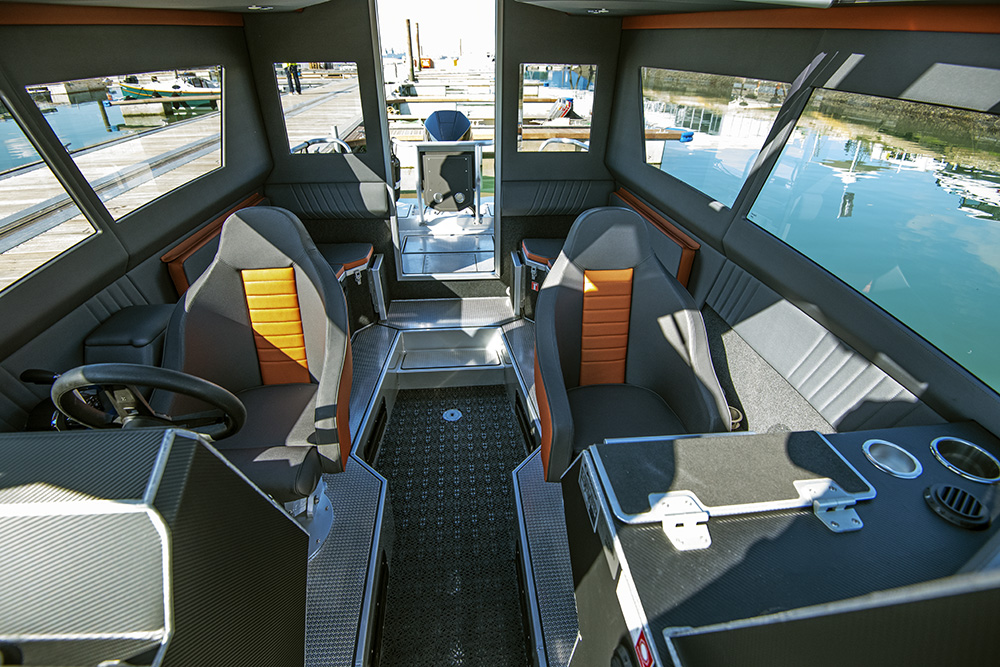 Ockelbo B25 CAB cabin interior with twin helm seats and wide windows overlooking marina.