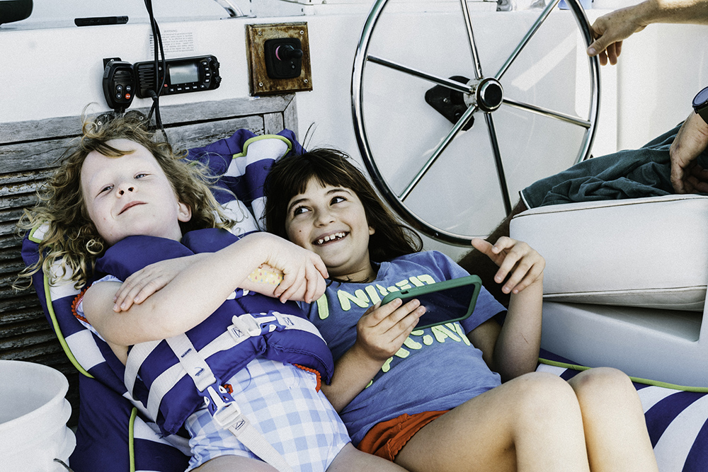 Two children cosied up on cushions on board a yacht