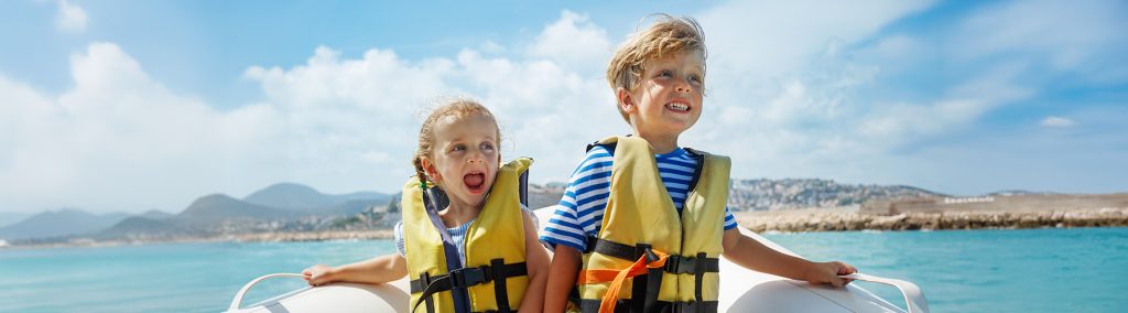 Two young children wearing lifejackets in a boat laughing