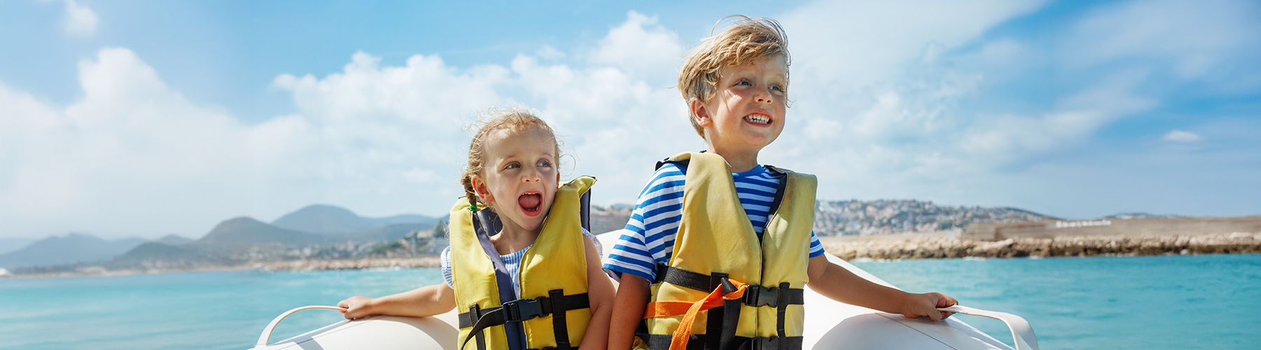 Two young children wearing lifejackets in a boat laughing