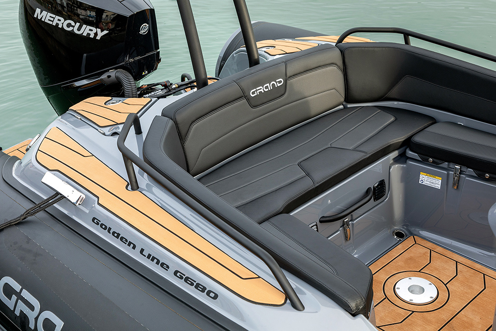 Bench seat at aft of a RIB in wraparound style in dark grey upholstery.