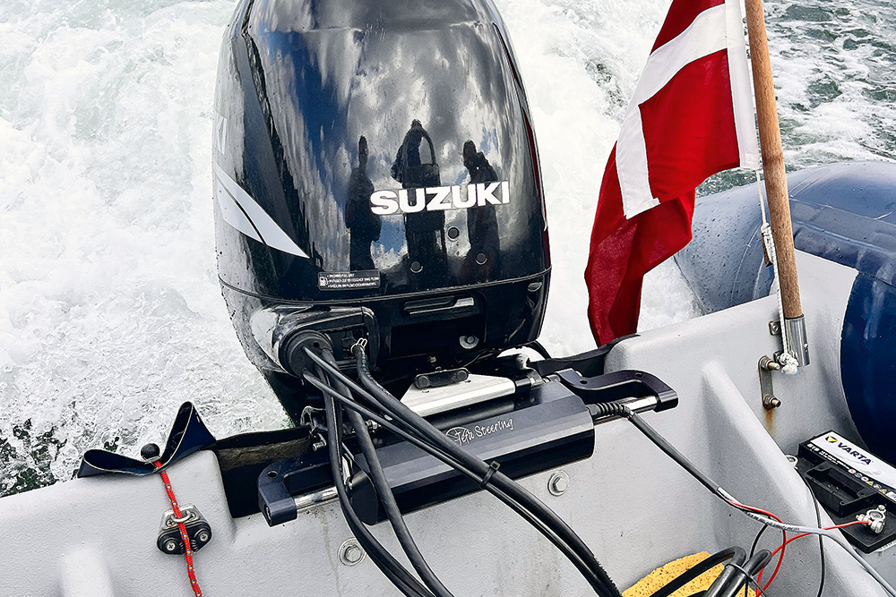 Transom-mounted Jeffa electric steering unit connected to a Suzuki outboard, shown underway.