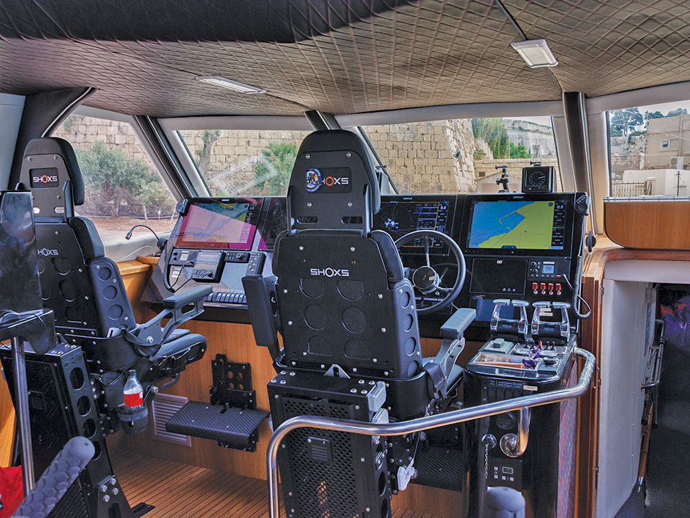 SHOXS shock-mitigating helm seats and a full navigation suite inside Thunder Child II’s bridge, showing multi-screen controls and steering position.