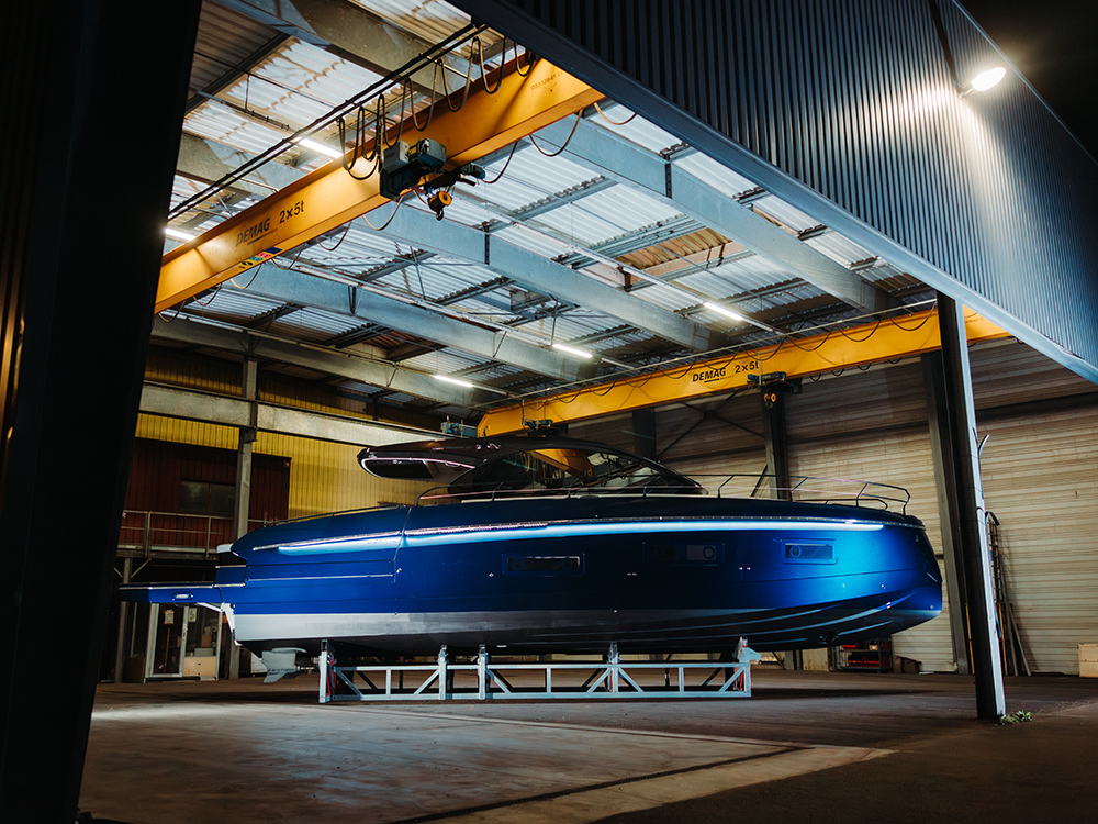 Sleek blue Beneteau Gran Turismo 50 Alpine edition displayed indoors on supports.