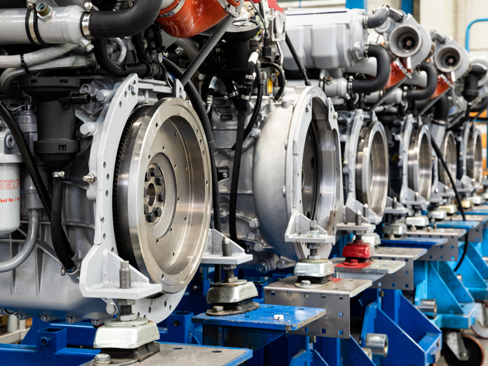 Row of Steyr marine diesel engines on assembly stands, showing flywheels, cooling systems and precision engineering details.