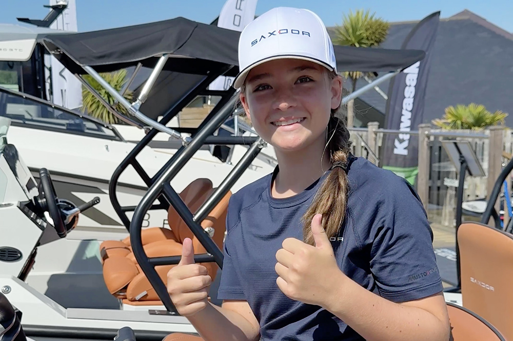 Girl wearing Saxdor branded hat smiling with both thumbs up