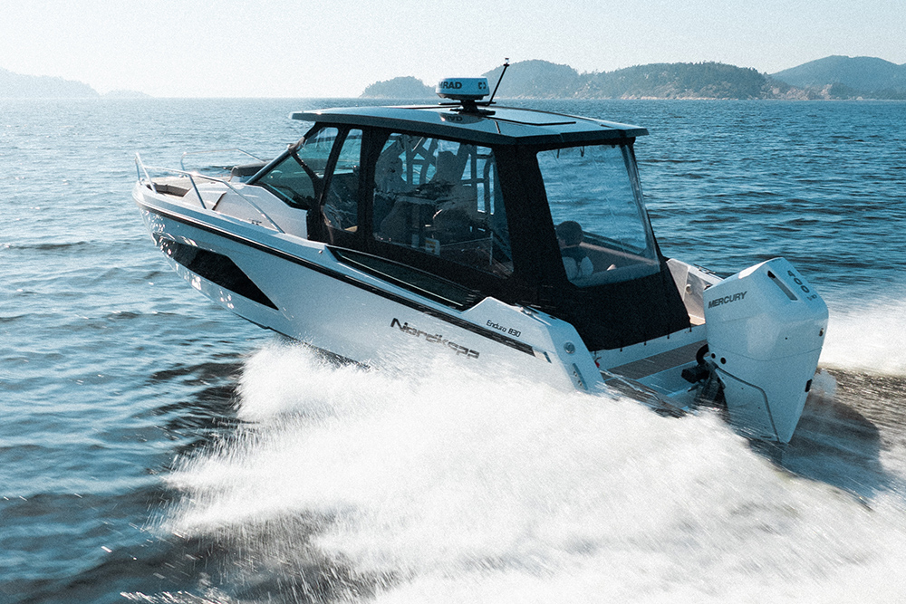 Nordkapp Enduro 830 with fully enclose canopy underway at speed with cliffs in the background