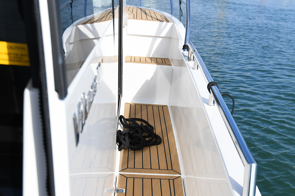 Teak decking to side walkways leading up to the bow area on the Viknes 10 with a black rope stored on the walkway