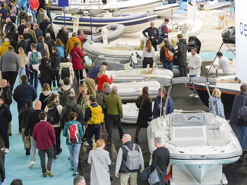 Crowds explore a busy boot Düsseldorf show hall lined with small motorboats and RIBs.