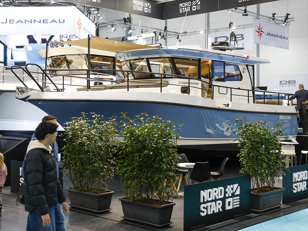 A Nord Star motorboat showcased on a raised stand at oot Düsseldorf, surrounded by plants, branding, and visitors moving through the exhibition.
