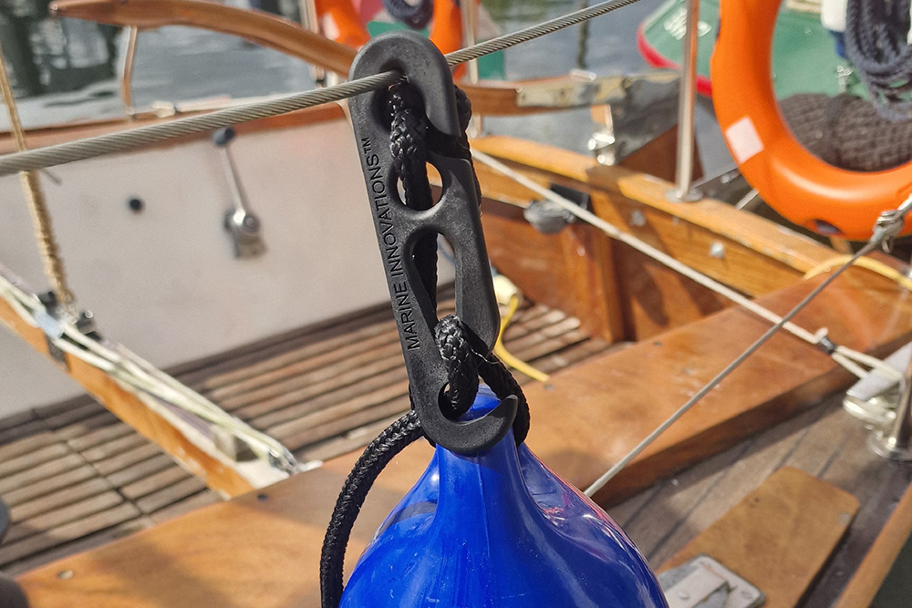 Fendermate clip attaching bright blue fender to side rail of yacht