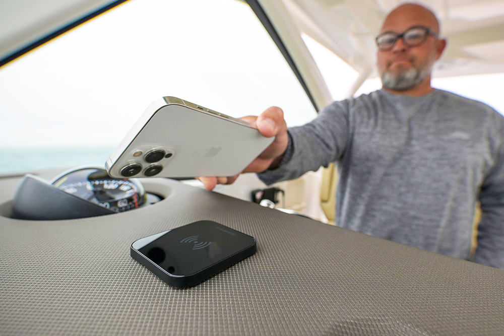 Man placing phone over a Scanstrut charging unit on boat dash