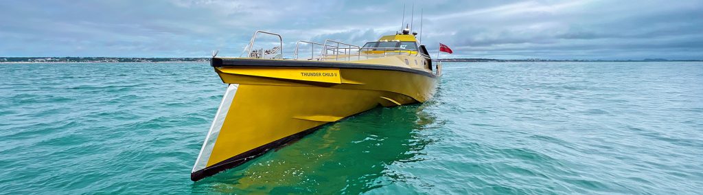 Big yellow powerboat called Thunder Child 2 with pointed bow on turoquoise sea