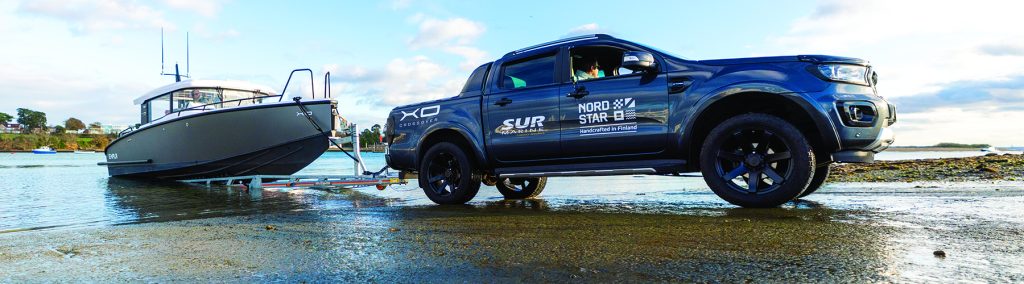 Pickup truck towing an XO trailer boat down a slipway, demonstrating flexible trailer boating and launch access at the water’s edge.