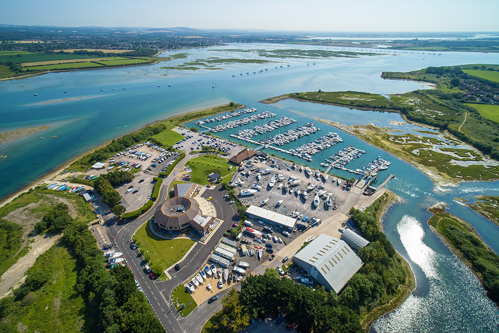 Aerial view of MDL's Northney marina with pontoons, boatyard and surrounding estuary, highlighting berths, facilities and access to open water.