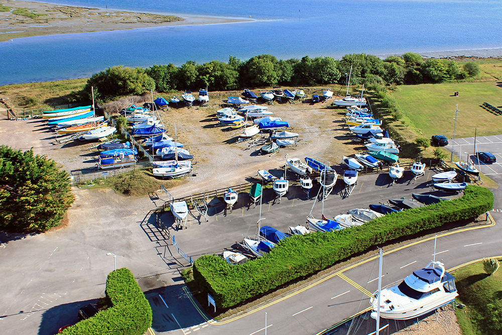 Aerial view of MDL's Northney trailer boat storage area which is beside an estuary, showing boats ashore, parking access and proximity to launch facilities.