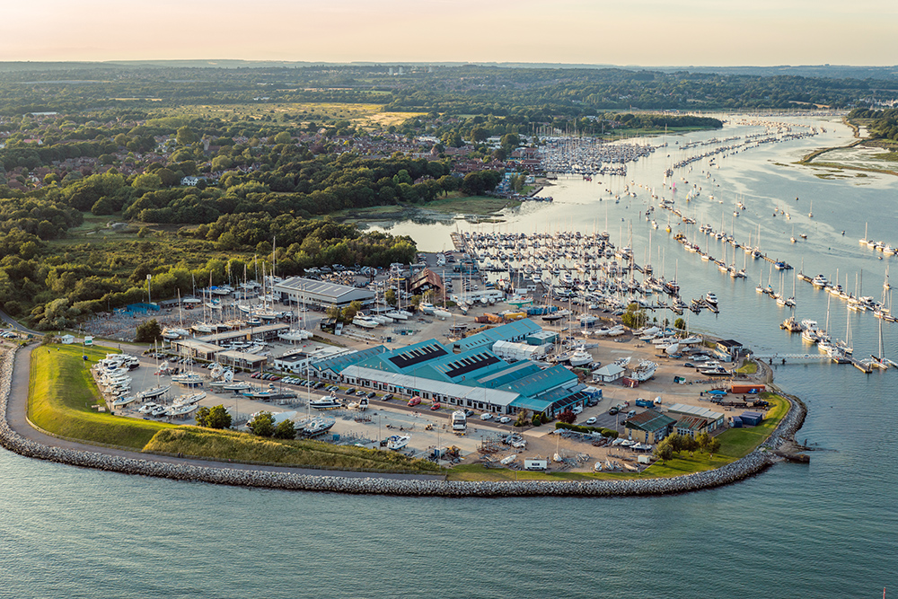 Aerial view of Hamble Marina, with pontoons, moorings and sailing traffic along a winding estuary.