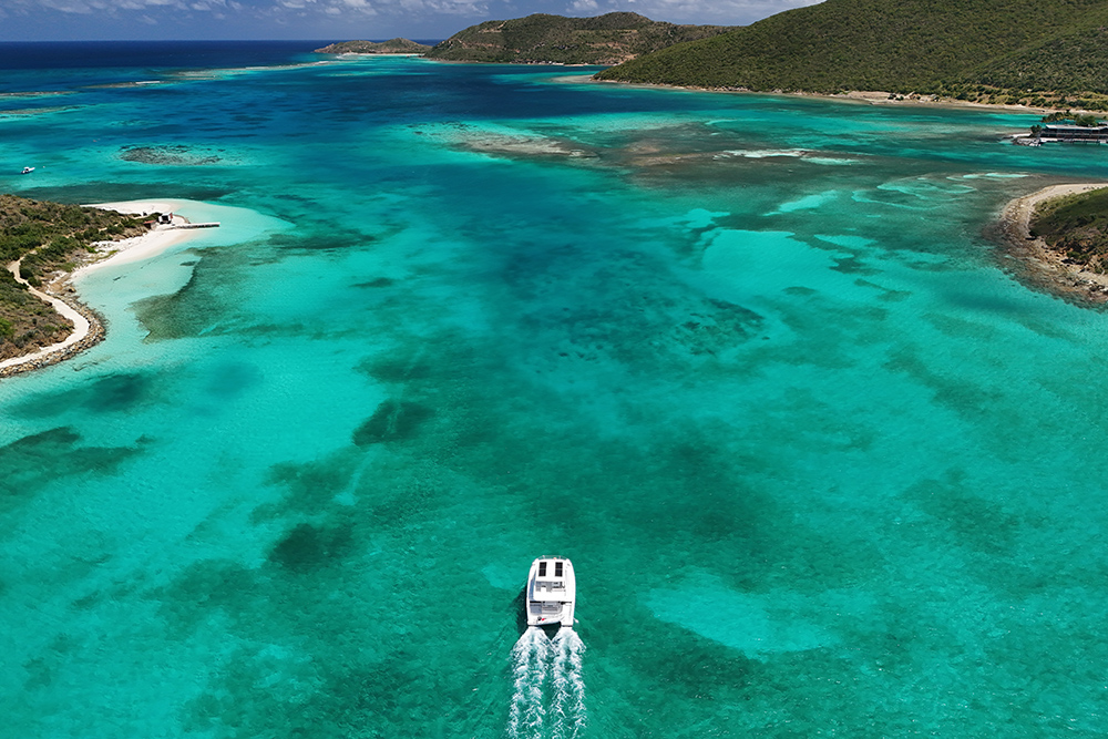 Power catamaran making way on turquoise sea through wooded small islands