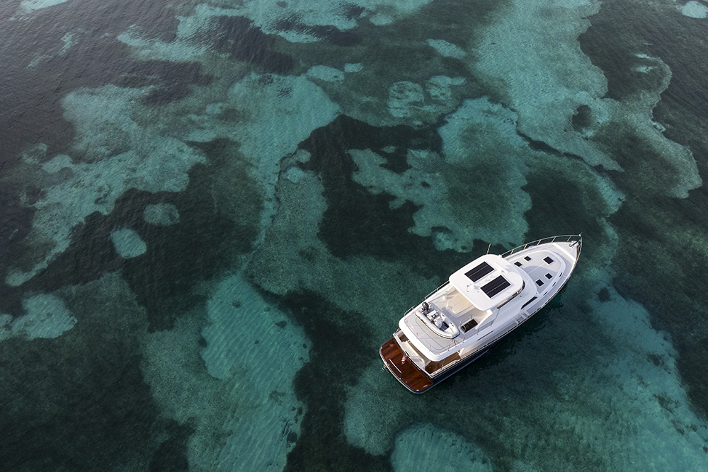 Aerial view of the Grand Banks 62 at rest in clear turquoise water, highlighting its deck layout, solar panels and refined long-range cruising design.