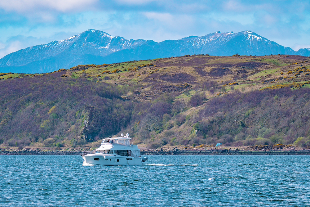 Motorboat arriving at Largs Yacht Haven, with mountains behind.