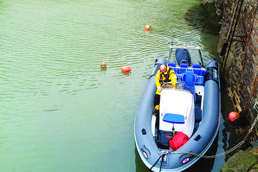 RIB moored alongside Porlock Weir quay with crew aboard in calm water.