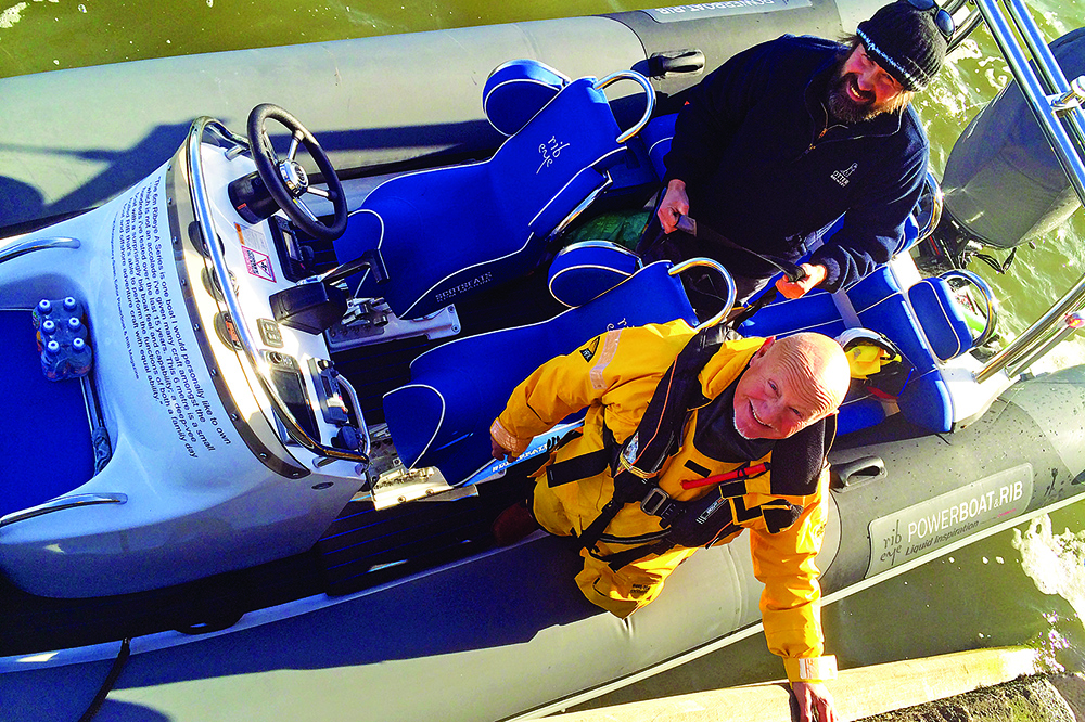 Crew in yellow foul-weather gear prepare to depart aboard a RIB moored alongside the quay.