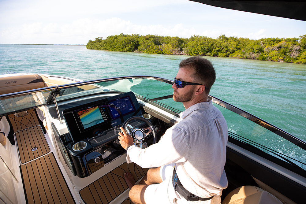 Helm view showing boater using Simrad multifunction display with integrated marine electronics while cruising calm coastal waters