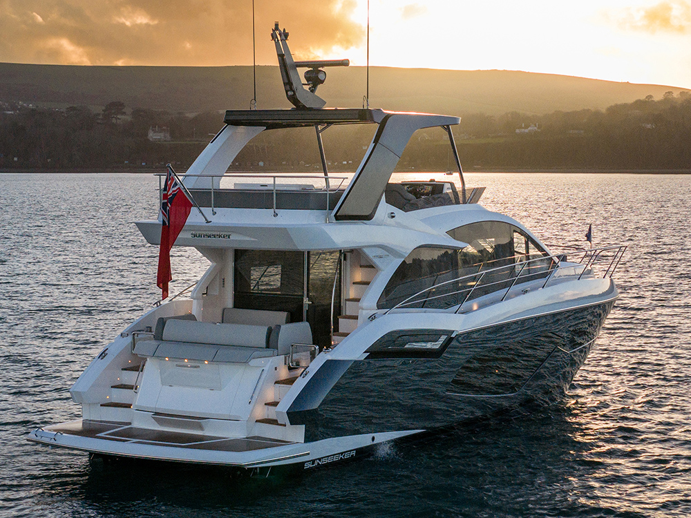 Sunseeker Manhattan 56 at anchor at sunset, highlighting flybridge, modular aft cockpit and panoramic hull windows.