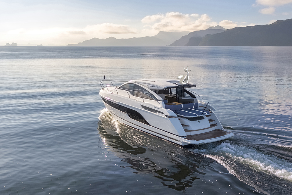 Fairline Targa motor yacht cruising offshore at sunset, showcasing sleek hardtop design and spacious aft cockpit.