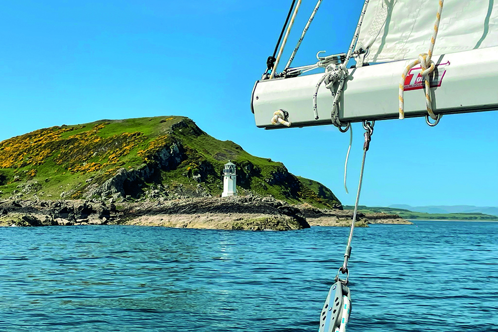 Yacht boom in foreground looking across to lighthouse on headland
