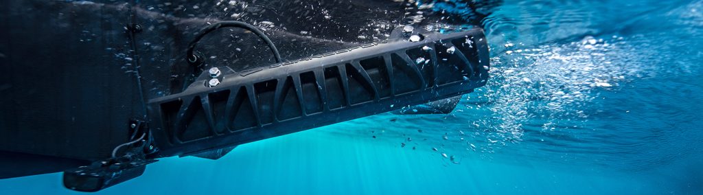 Underwater view of fitted Seakeeper RIDE underway in turquoise sea with white bubbles.