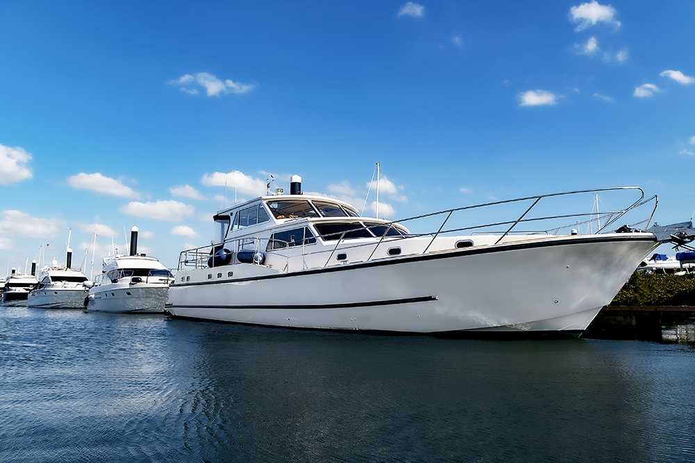 Motor yachts moored at Troon Yacht Haven marina under blue skies.