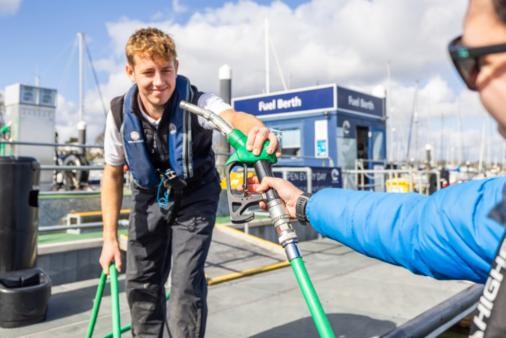 Marina staff hands fuel nozzle to boater at MDL fuel berth, refuelling powerboat at dock during boating season