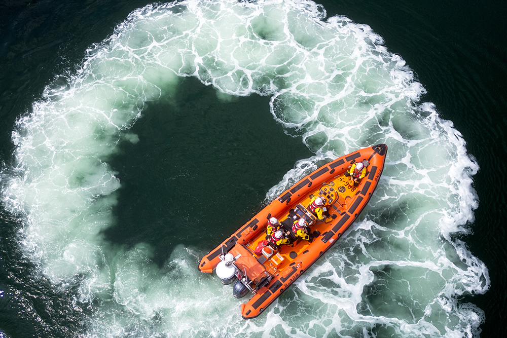 RNLI lifeboat conducting manoeuvres, creating circular wake during live demonstration at Plymouth Boat Fest