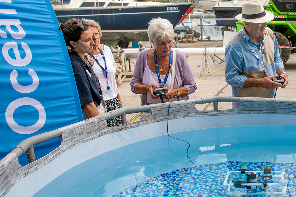 Visitors enjoying marine technology demo in test pool at Plymouth Boat Fest, with remote control vessel and exhibitors
