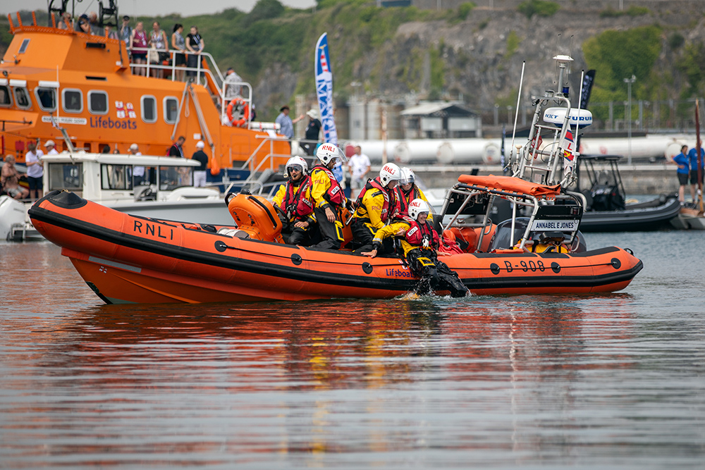 RNLI crew performing water rescue drill from lifeboat during live demonstration at Plymouth Boat Fest