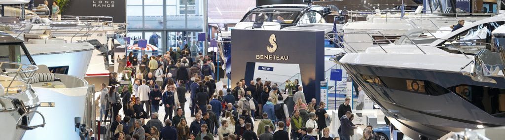 Lots of people walking in the aisles of boot Dusseldorf boat show with motorboats on display either side