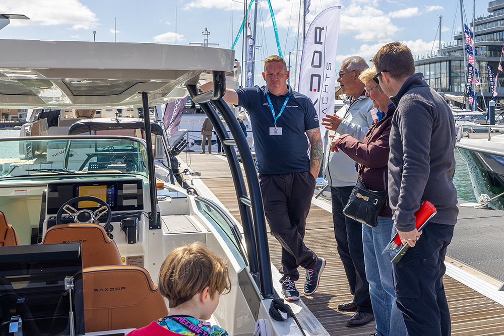 Sales representative talks to family about a displayed boat at the South Coast & Green tech boat show in 2025
