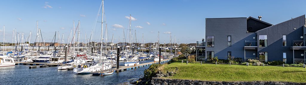 Troon Yacht Haven marina with moored yachts, pontoons and modern waterfront building on Ayrshire coast under clear skies.